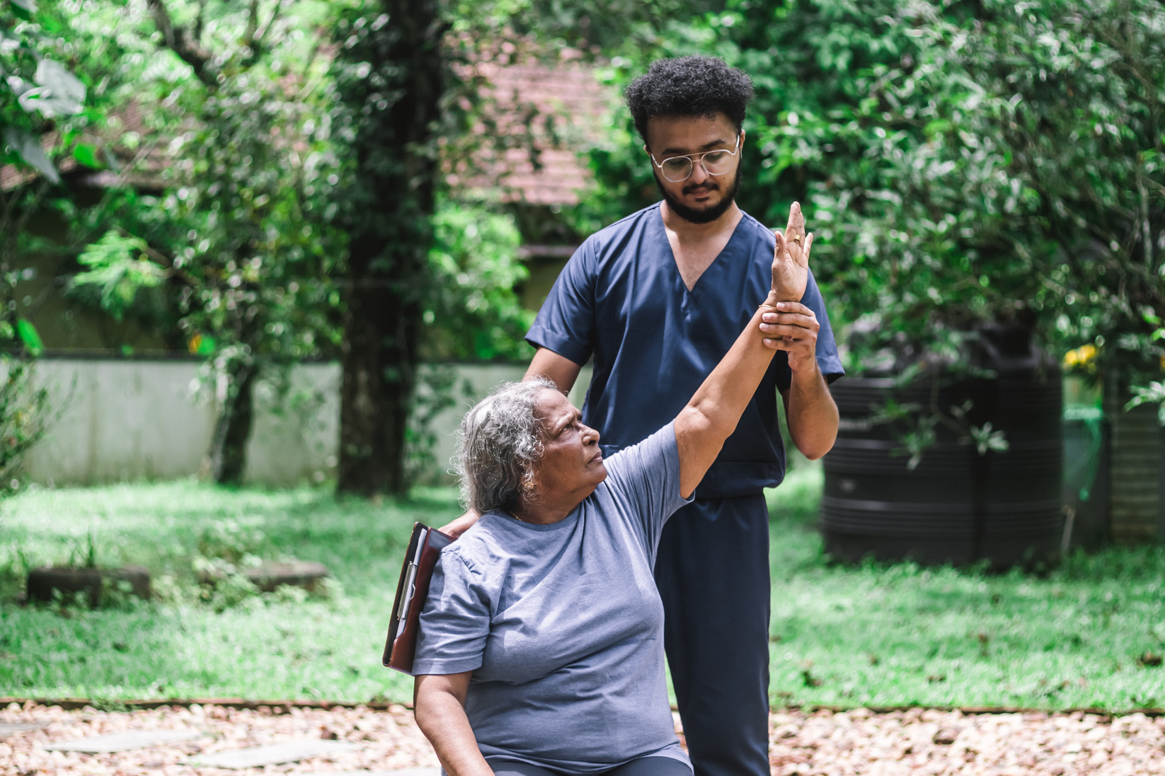 Male Nurse Helping an Elderly Woman Exercising Outdoors